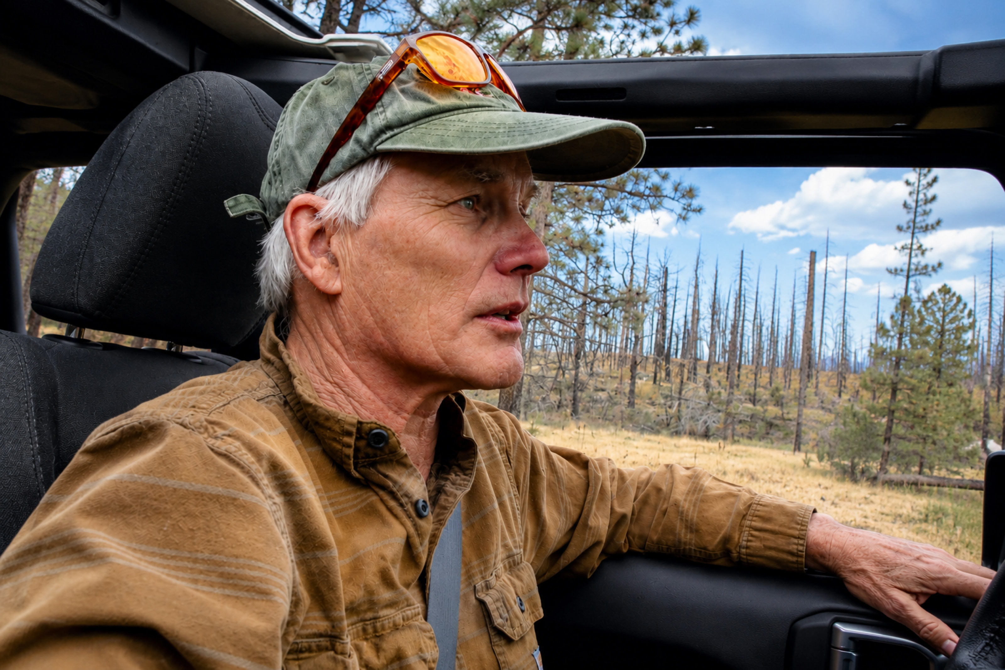 A scientist in the field beside a vehicle under a wide open sky.